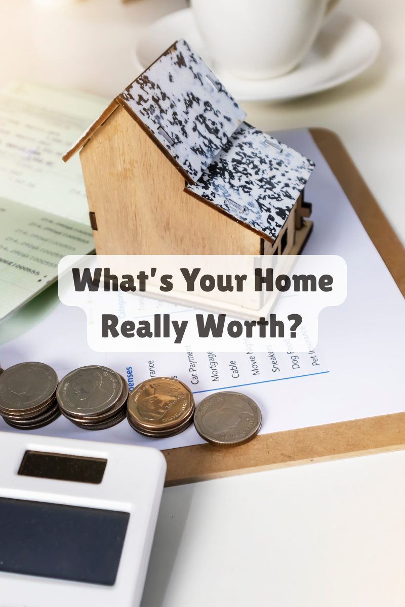 Miniature wooden house with stacked coins and calculator on a clipboard, symbolizing home valuation and equity review.
